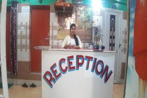 a woman standing behind a counter with the word reception at Goroomgo Om Sai Residency Bhubaneswar in Bhubaneshwar