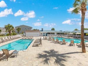 a pool with lounge chairs and a palm tree at Colony 221 in Tybee Island