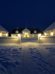 a house with lights in the snow at night at Bulagergaard in Vejen