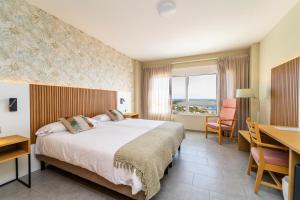 um quarto de hotel com uma cama grande e uma secretária. em Hotel Vistamar Wellness by DLV em Villajoyosa