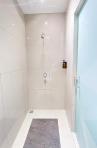 a white bathroom with a shower with a glass door at Parkside Alhambra Hotel Banda Aceh in Banda Aceh