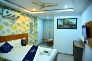 a bedroom with a bed and a tv in a room at Hotel Housefinch Residency in Bangalore