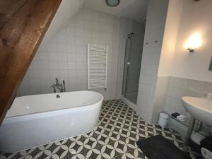 een badkamer met een bad en een wastafel bij B&B Het Wellnest in Hulshorst