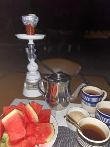 a table with a plate of watermelon and cups of tea at Upper Hill Place in Dar es Salaam
