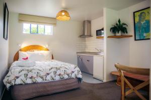 a small bedroom with a bed and a kitchen at Futuna Rocks Motel in Kaikoura