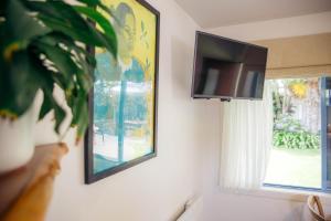 a flat screen tv hanging on a wall next to a window at Futuna Rocks Motel in Kaikoura