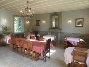 une salle à manger avec des tables et des chaises ainsi qu'un lustre dans l'établissement Manoir De Savigny, à Valognes