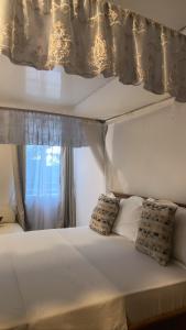 a white bed with two pillows in front of a window at Upper Hill Place in Dar es Salaam