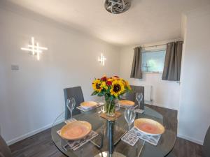 a dining room with a glass table with flowers on it at High Trees in Bodham