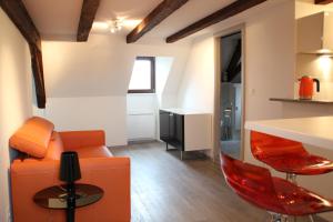 sala de estar con sofá naranja y sillas rojas en A L'ill - Apparts & Studios Strasbourg Hyper Centre, en Estrasburgo