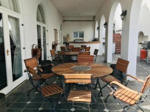 un patio con mesa de madera y sillas en Waterkloof Mansion Boutique Hotel en Pretoria