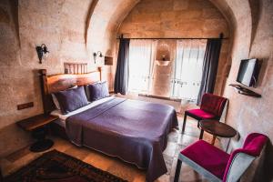 a bedroom with a bed and two chairs and a television at APEX CAVE HOTEL in Goreme