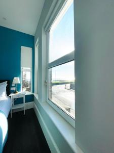 a bedroom with a large window with a bed and a desk at Coral House in Gorleston-on-Sea