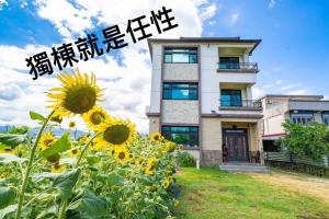 a building with a field of sunflowers in front of it at 馬在對面民宿 in Yilan City