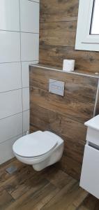 La salle de bains est pourvue de toilettes blanches et de murs en bois. dans l'établissement במרכז הכפר, à Majdal Shams