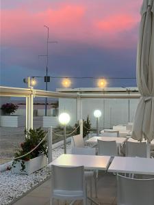 un restaurante con mesas y sillas blancas y el océano en Casa Pomposa, en Lido di Pomposa