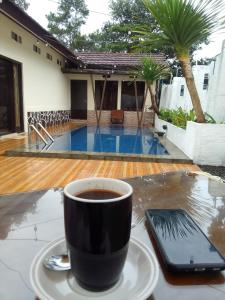 eine Tasse Kaffee auf einem Tisch mit einem Handy in der Unterkunft Nyaman in Bogor