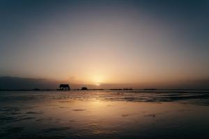 a sunset on the beach with the sun setting in the distance at Seaside 43 in Sankt Peter-Ording