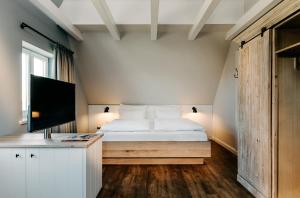 a bedroom with a bed with a television and a desk at Seaside 43 in Sankt Peter-Ording