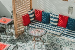 a room with a couch with colorful pillows and a table at Riad Dar Abi in Essaouira +44 photos