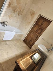 een badkamer met een bad en een toilet en een houten deur bij Waterkloof Mansion Boutique Hotel in Pretoria
