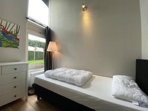 een slaapkamer met een wit bed en een raam bij Grevelingenlaan 30,Modern ingerichte Bungalow aan de Grevelingen, in Scharendijke