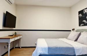 a bedroom with a bed and a desk with a television at Royal Park- Magical garden apartment in Eilat