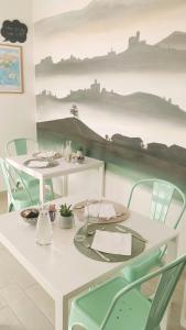 a white table with green chairs and a table with plates at B&B Le Albarelle in Alba