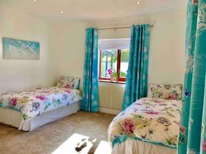 a bedroom with two beds and a window at Honeyacres in Down Hatherley