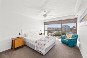 ein Schlafzimmer mit einem Bett und einem Stuhl und einem Fenster in der Unterkunft Gemini Court Holiday Apartments in Gold Coast + 148 Fotos