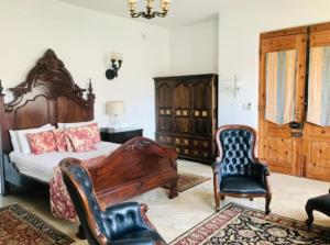 een slaapkamer met een bed en 2 stoelen bij Waterkloof Mansion Boutique Hotel in Pretoria