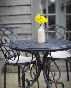 a black table with a vase with a yellow flower in it at Hut Haf in Talacre