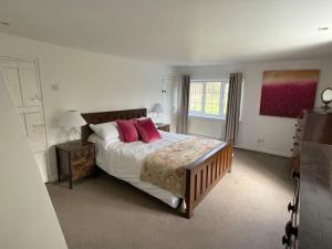 a bedroom with a bed with red pillows and a window at Entire country farmhouse in Cardiff