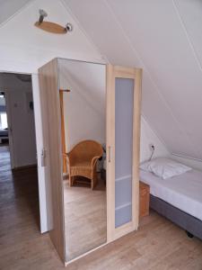 een kleine kamer met een bed en een spiegel bij Het Zwaluwnest 69 in Giessenburg