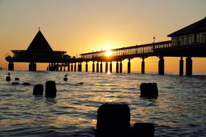 ein Pier im Wasser mit Sonnenuntergang in der Unterkunft Das Handtuchhaus - Wohnen im schmalsten Haus - Mittendrin in Heringsdorf