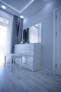 a white dresser in a white room with a mirror at beautiful and comfortable apartment in the city center in an architectural building in Baku