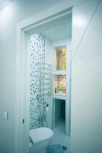 a white bathroom with a toilet and a window at beautiful and comfortable apartment in the city center in an architectural building in Baku