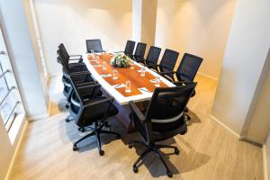 a conference room with a long table with black chairs at Marine Inn Hotel in Cochin