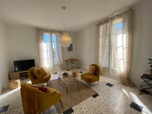un salon avec des chaises jaunes et un lustre dans l'établissement Le Chai des Tuileries, à Montagnac