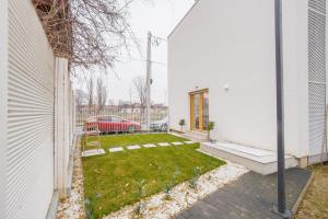 um quintal com um pequeno quintal ao lado de uma casa branca em Urban Garden by Waterview em Oradea