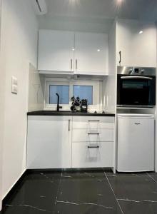 a kitchen with white cabinets and a black counter top at ATH-Brand new 2bedroom apartment in Athens