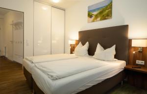 a bedroom with a large bed with white sheets and pillows at Lounge Maritime direkt am Meer, Strand fußläufig erreichbar, barrierefrei in Kappeln