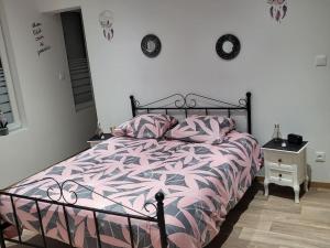 um quarto com uma cama com um edredão rosa e branco em chez Aline em Calais