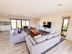 a living room with two couches and a flat screen tv at London Bridge Holiday Home in Port Campbell