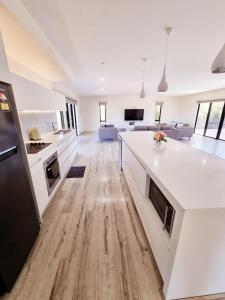 a kitchen and living room with white cabinets and wood floors at London Bridge Holiday Home in Port Campbell