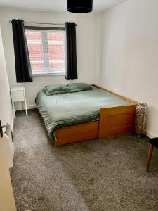 a small bedroom with a bed with a window at Large 2 bedroom apartment, 4 beds one 1 en-suite, Free parking Nr Chelt Elmore and Quays in Gloucester