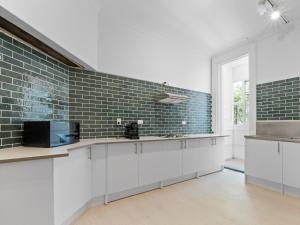a kitchen with white cabinets and a brick wall at Potts Point Budget Stay - Near Kings Cross Station - Self Check-in in Sydney