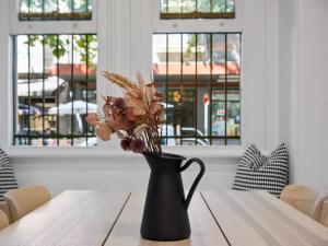a black vase with flowers sitting on a table at VENUS Potts Point - FEMALE ONLY HOSTEL - Long stay negotiable in Sydney