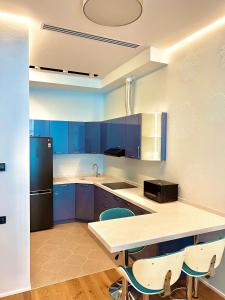 a kitchen with blue cabinets and a black refrigerator at Baku, SEA BREEZE on the shores of the Caspian Sea in Bilgah