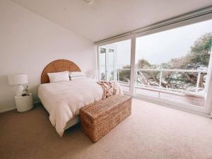 a bedroom with a bed and a large window at The Cove Beach Front Luxury House in Port Fairy